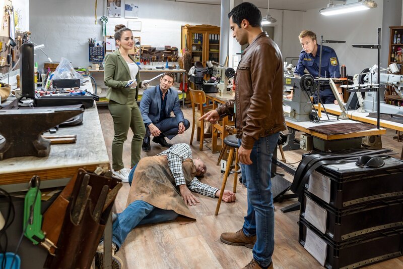 Pathologin Atay (Sevda Polat, l.) kann den Ermittlern Hansen (Igor Jeftić, 2.v.l.) und Kaya (Baran Hêvî, 2.v.r.) sowie Polizeihauptmeister Mohr (Max Müller, r.) bereits am Tatort sagen, dass das Opfer (Komparse, M.) mit einem Polsterpilz getötet wurde. – Bild: ORF/​ZDF/​Linda Gschwentner