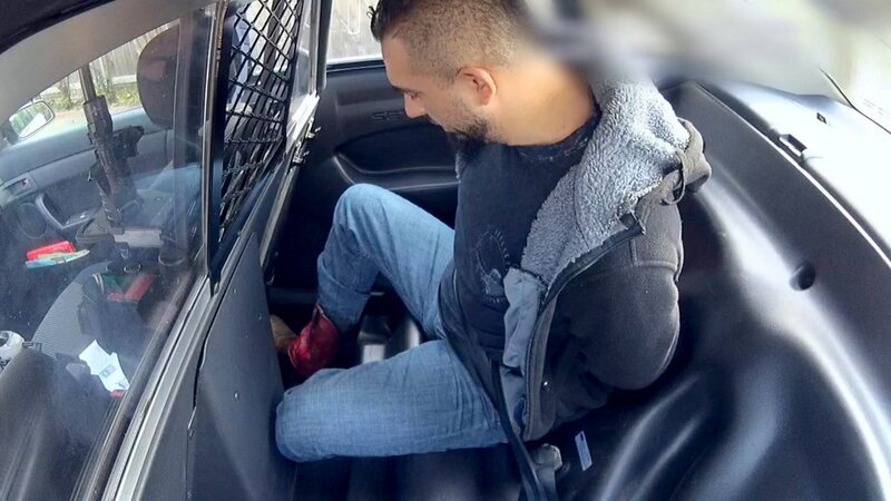 Ein Mann, gefesselt und auf dem Rücksitz eines Polizeifahrzeugs sitzend. – Bild: Crime + Investigation