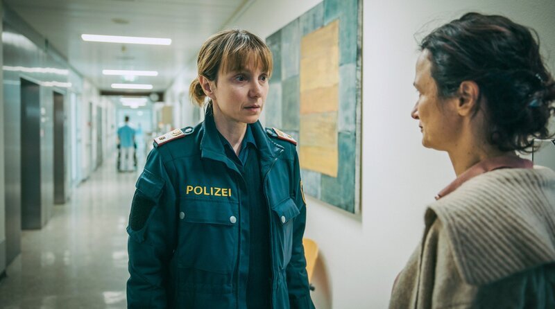 Pia (Julia Koschitz, l.) wird im Krankenhausgang von der wütenden Oksana (Veronika Glatzner) daran gehindert, den verletzten Roman zu besuchen. – Bild: ARD Degeto Film/​ORF/​Mona Film/​Victoria Herbig