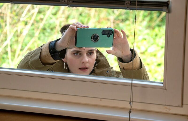 Reporterin Louisa Malottky (Vanessa Loibl) beobachtet das Gespräch und fotografiert durch das Fenster. – Bild: NDR /​ Oliver Feist