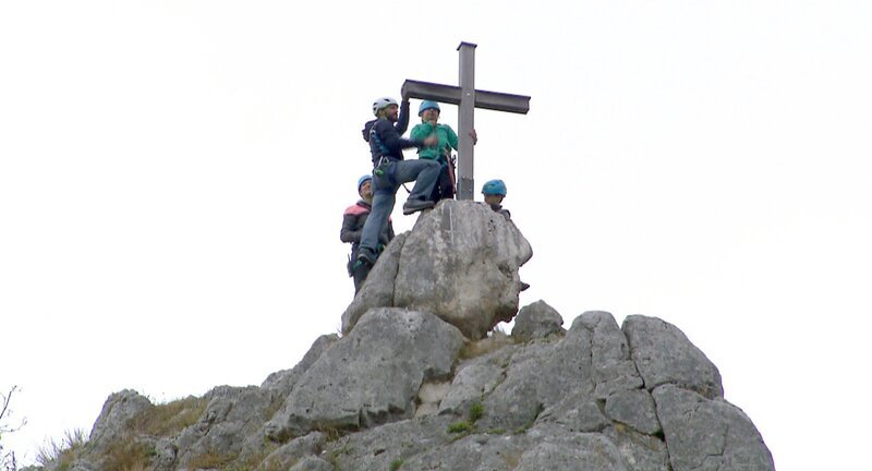 Hoch oben am Gipfelkreuz ist die Klettergruppe nun angekommen! (v. l. n. r.) Maral, Klettertrainer Martin, Melina und Bruder Fabio. – Bild: SWR