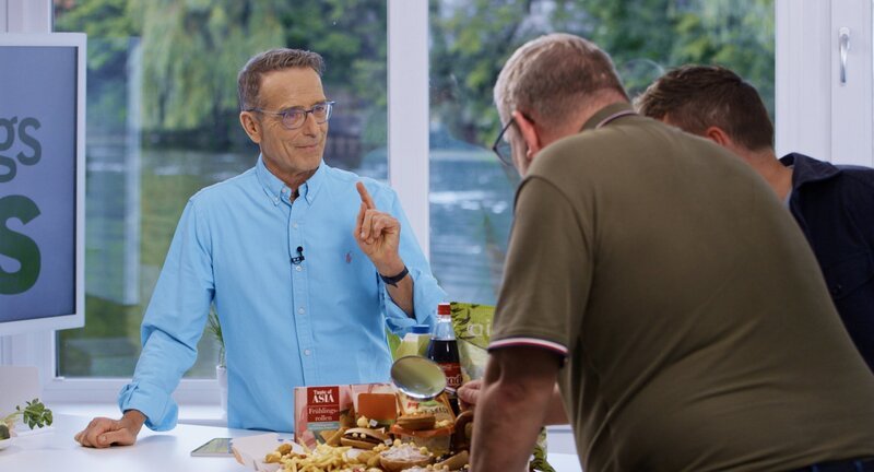 Was steckt drin? Matthias Riedl weist Sven K. und seinen Mann Adrian auf die vielen Zusatzstoffe in ihrem Essen hin. Zukünftig sollen die beiden auf natürliche Lebensmittel setzen. – Bild: NDR/​Moritz Schwarz