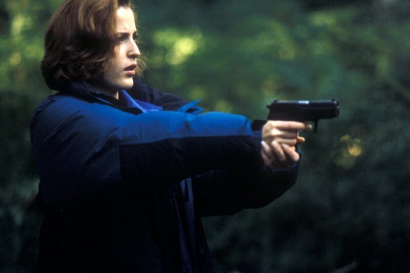 Scully (Gillian Anderson) zielt auf einen unsichtbaren Gegner, den sie zunächst für ein Raubtier hielt. – Bild: ProSieben MAXX