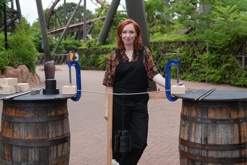 Hannah Fry demonstriert im Thorpe Park eine Konstruktion aus Rohrstahl. – Bild: RTL /​ BBC Studios /​ Achterbahn
