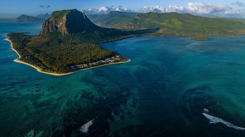 Der 556 Meter hohe Le Morne im Südwesten von Mauritius ist das Wahrzeichen der Insel. Eine weitere Attraktion ist die optische Täuschung am Fuße des Felsens: Das Korallenriff und Sandwirbel lassen es so aussehen, als ob ein riesiger Wasserfall zum Grund des Indischen Ozeans stürzt. – Bild: Martina Andrés /​ Doclights /​ NDR Naturfilm /​ Terra Mater Studios GmbH