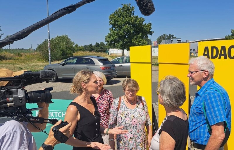 Auf der A14-Autobahnraststätte Muldental Süd (bei Grimma): Reporterin Juliane Zeisler (2. von links) im Gespräch mit Reisenden über das Image des ADAC. Unter anderem sollen sie erraten, welches das ADAC-Gelb ist. – Bild: MDR/​Alexander Kirmse