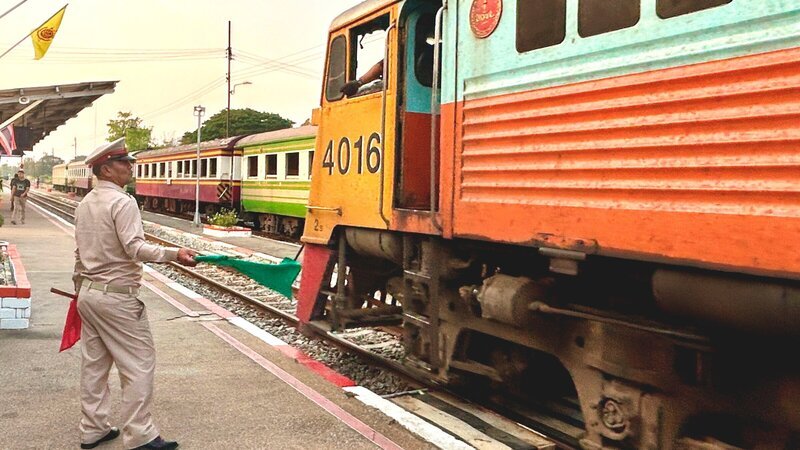 Mit grünen Fahnen geben die Fahrdienstleiter an den thailändischen Bahnhöfen die Einfahrt frei. – Bild: 3sat