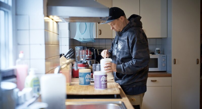 Setzt praktisch nur auf Proteine: Weil es schnell geht, rührt sich Dennis H meist einfach einen Shake an. Er hat das bei verschiedenen Influencer*innen gesehen. – Bild: NDR/​Oliver Zydek