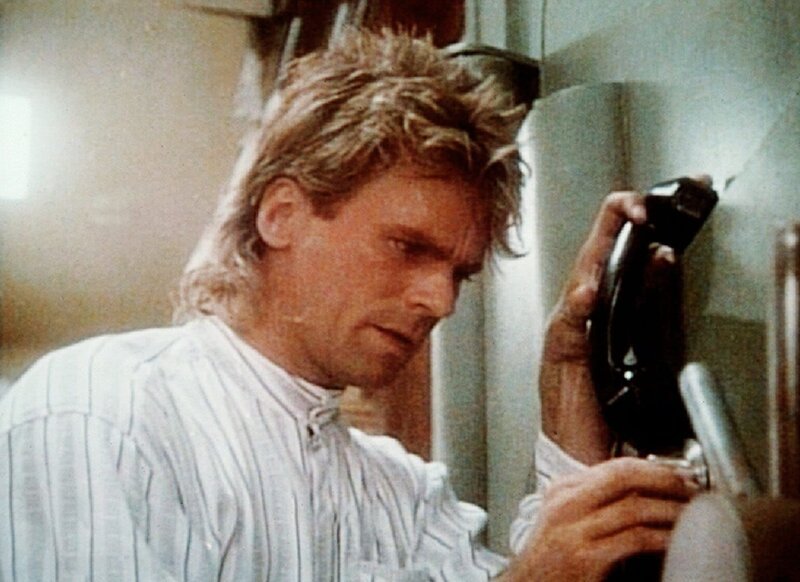 Mittels Telefonhörer und Lautsprecher versucht MacGyver (Richard Dean Anderson), einen Safe zu öffnen. – Bild: Kabel Eins Classics