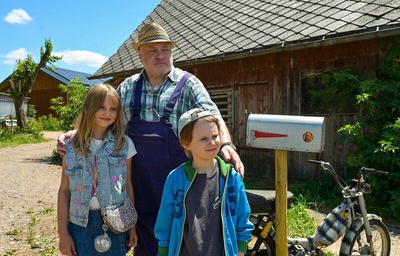 Bauer Merz (Georg Blumreiter, Mitte) bekommt Besuch von seinen Enkelinnen Jack (Holly Herrlein, rechts) und Olivia (Laetitia Frey, links). – Bild: SWR/​Maria Wiesler