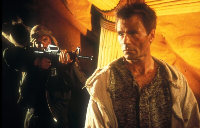 Colonel Jack O’Neill (Richard Dean Anderson) wird von einem Soldaten, der ein Bewohner des fremden Planeten ist, mit einer Waffe bedroht. Wird sich der Colonel befreien können? Stargate – Das erste Gebot – Bild: Tele 5