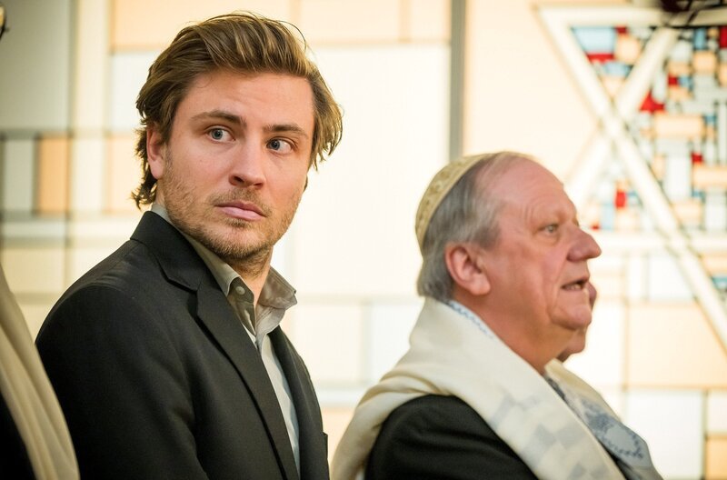 Wanja (Jannik Schümann) ist eifrig bestrebt, während des Gottesdienstes in der Synagoge alles genauso zu machen wie die anderen Männer, um nicht als Schwindler aufzufallen. – Bild: SWR/​Odeon Fiction/​Zuzana Panska