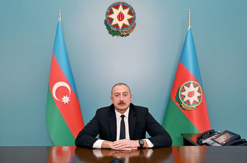 Aserbaidschans Präsident Ilham Aliyev flankiert von Nationalflaggen und Staatswappen: Die politische Führung in Baku tritt im Konflikt um Berg-Karabach zunehmend selbstbewusst auf – gestützt durch militärische Stärke und wachsenden geopolitischen Einfluss. – Bild: Press Service of the President of the Republic of Azerbaijan