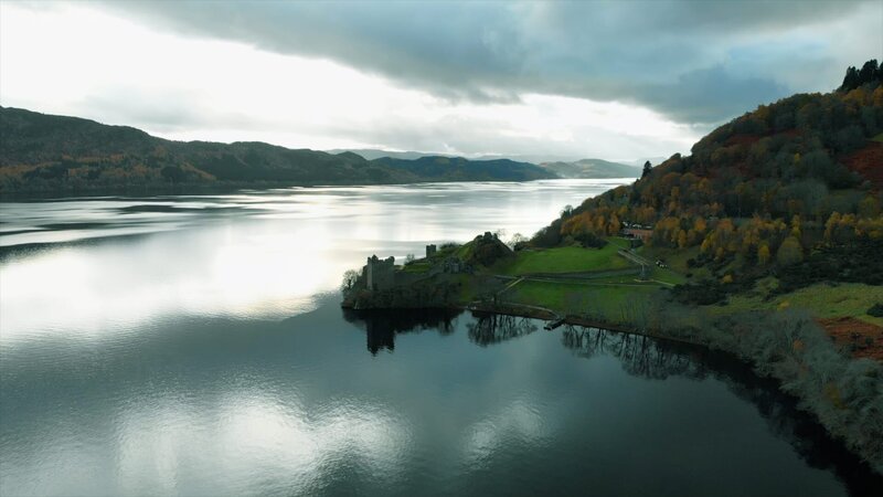 Luftbildaufnahme eines Schlosses in Schottland am Loch Ness mit der Spiegelung des hellen, bewölkten Himmels – Bild: RTL /​ Creatas Video+ /​ Getty Images
