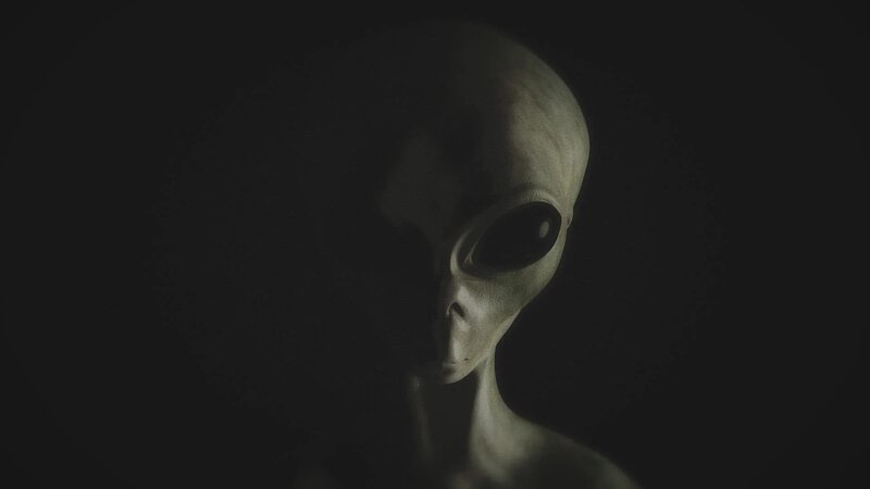 Eine Darstellung eines grauen Aliens, dessen Gesicht teilweise im Dunkeln verborgen ist. – Bild: The Movie Database (TMDb)