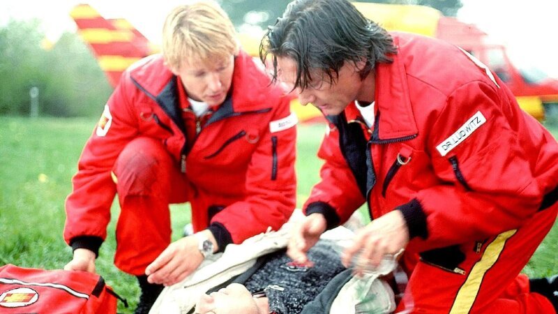 Berger (Serge Falck, l.) und Dr. Lüdwitz (Rainer Grenkowitz, r.) treffen am Unfallort ein und versorgen den verletzten Troger (Christian Oskar Spitzl). Was sie nicht ahnen: Seine Tochter verzweifelt in einem führerlosen Fesselballon am Himmel&nbsp;… – Bild: MG RTL D /​ Helene Waldner