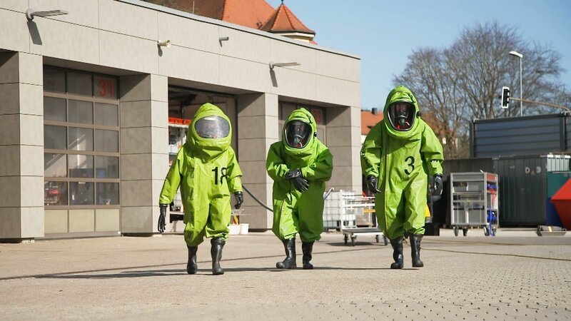 Fabian Schweinsteiger, Johannes Winkler and Simon Kargl wearing chemical protective suits during a practice in the fire station’s yard. – Bild: Warner Bros. Discovery /​ Editorial Team Janus
