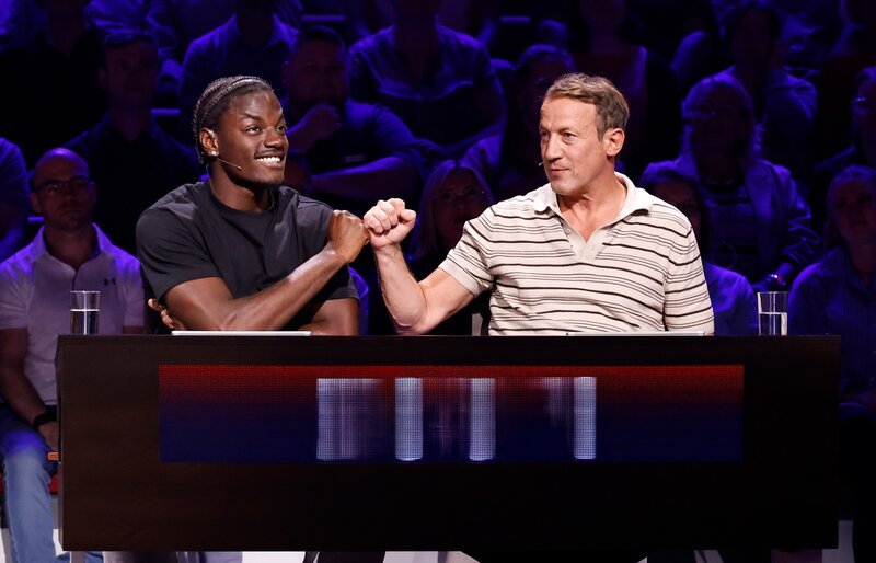 Rateteam-Kapitän Wotan Wilke Möhring (r.) mit Model und Social Media Creator Ibrahim „Ibo“ Ouro-Bodi (l.). – Bild: ARD/NDR/UFA SHOW & FACTUAL/Morris Mac Matzen Rateteam-Kapitän Wotan Wilke Möhring (r.) mit Model und Social Media Creator Ibrahim „Ibo“ Ouro-Bodi (l.). – Bild: ARD/NDR/UFA SHOW & FACTUAL/Morris Mac Matzen