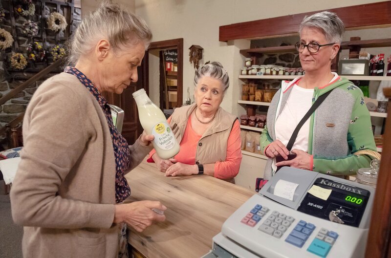 Die unzufriedene Kundin Frau Traub (Martina Benz) beschwert sich über saure Fallermilch bei Johanna (Ursula Cantieni, li.) im Hofladen. Leni (Heidi Vogel-Reinsch, Mi.) hört und schaut natürlich neugierig zu. – Bild: SWR/​Alexander Kluge