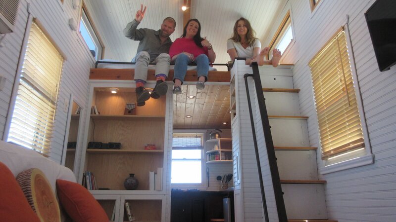 After climbing the steep stairs of this Texas tiny home, Lisa (right), along with friend Tara (center) and agent Jean assess the space of the storage loft across from the sleeping loft, as seen on Tiny House Hunters. – Bild: Discovery Channel